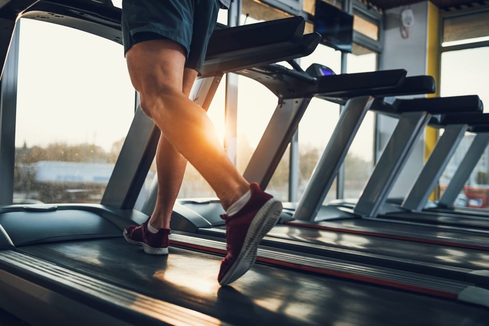 Osoba biegnąca na bieżni w siłowni — cardio vs trening siłowy