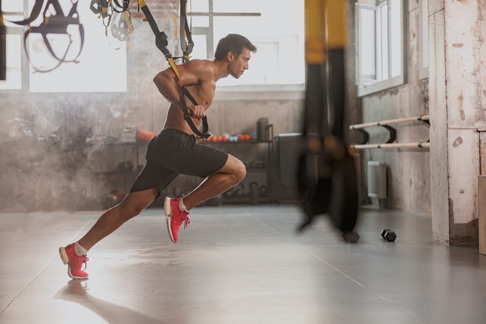 Mężczyzna ćwiczący na TRX w siłowni — trening na taśmach