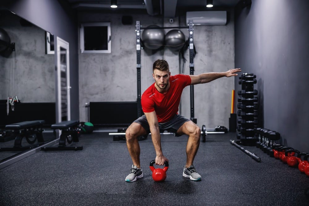Mężczyzna ćwiczący z kettlebellem na siłowni — trening z odważnikiem kulowym